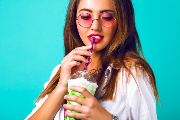 Portrait intérieur d'une femme assez mignonne buvant un délicieux milk-shake vert