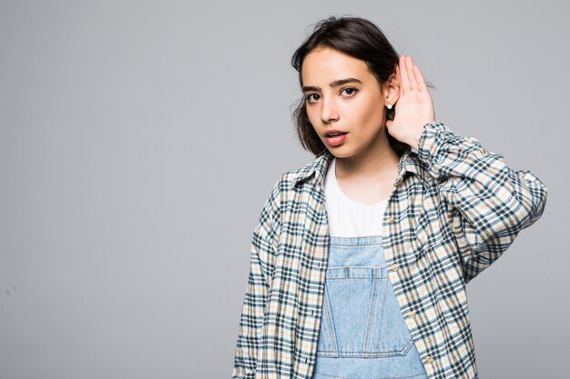 Portrait intérieur de jeune femme intéressante, tenant la main près de l'oreille debout.