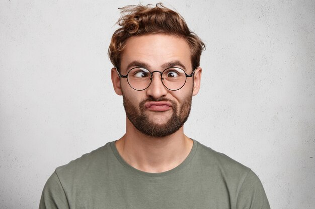 Portrait intérieur de jeune homme barbu avec une coiffure à la mode