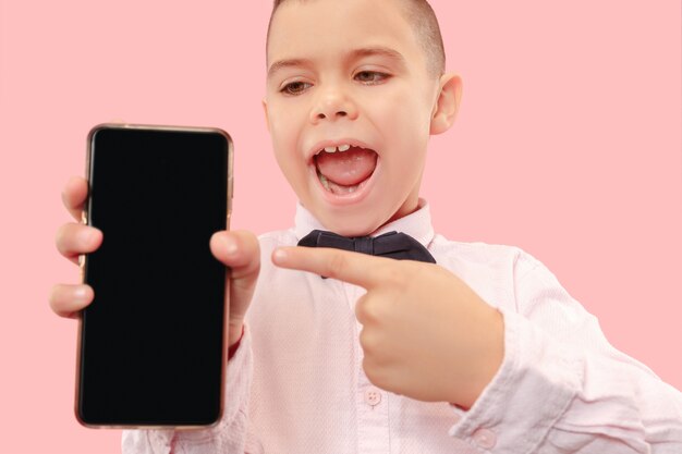 Portrait intérieur de séduisant jeune garçon tenant un smartphone vierge