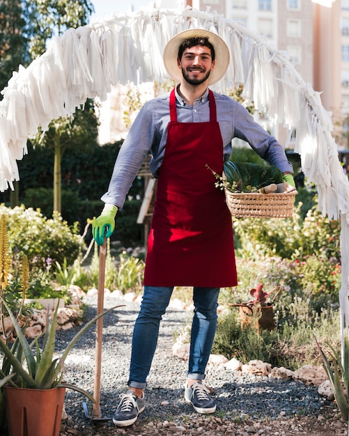 Portrait, jardinier, debout, houe, panier, mains