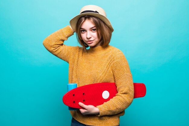 Portrait, de, jeune, adolescent, femme, dans, lunettes soleil, et, chapeau, tenue, skateboard, quoique, debout, isolé, sur, mur vert