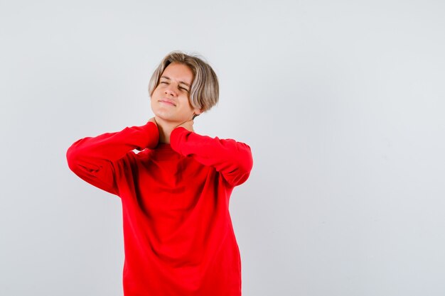 Portrait de jeune adolescent souffrant de douleurs au cou en pull rouge et à la vue de face dérangé