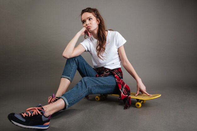 Portrait d'une jeune adolescente assise sur une planche à roulettes