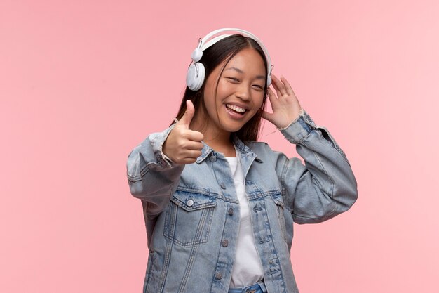 Portrait de jeune adolescente avec des écouteurs donnant les pouces vers le haut