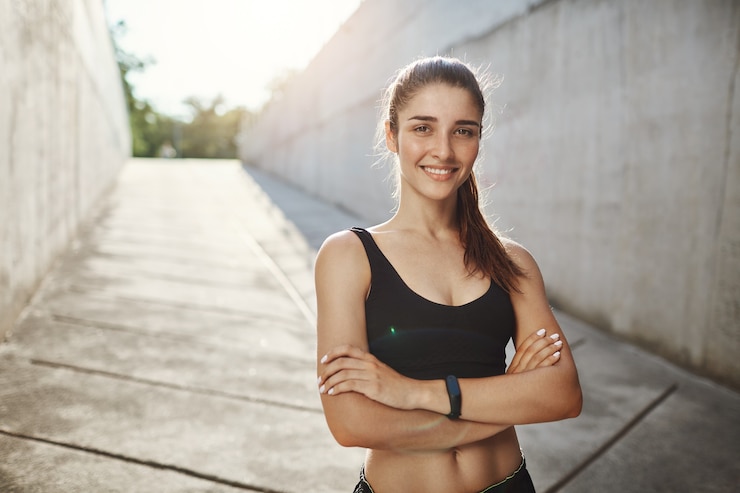 Photo gratuit portrait de jeune amateur de sport féminin debout confiant prêt pour l'entraînement habituel de la ville. rester en forme dans un environnement urbain.