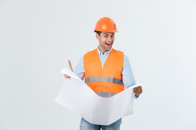 Portrait de jeune architecte heureux avec casque et plans intérieurs.