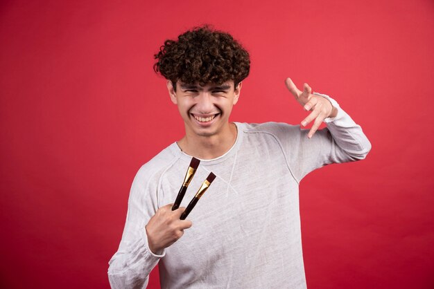 Portrait d'un jeune artiste masculin avec des pinceaux pour la peinture.