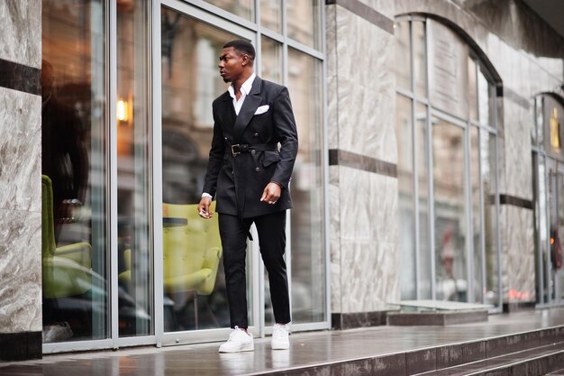 Portrait de jeune et beau homme d'affaires afro-américain en costume et baskets blanches