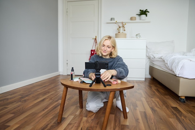 Photo gratuite portrait d'une jeune et belle blogueuse de style de vie qui parle de maquillage sur un vlog enregistré par une caméra