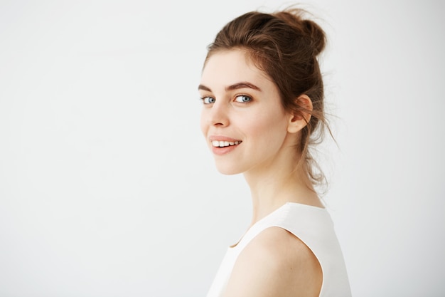 Portrait de jeune belle femme brune de profil souriant.