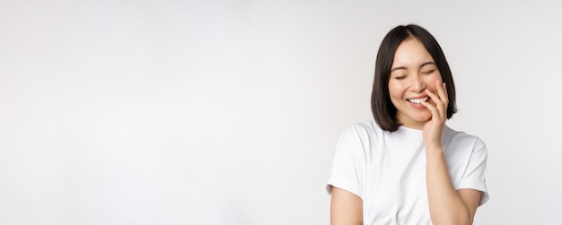 Portrait de jeune belle femme coréenne fille riant et souriant à la coquetterie debout à nouveau