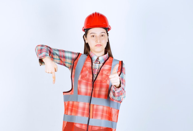 Photo gratuite portrait de jeune belle femme ingénieur en casque pointant quelque part.