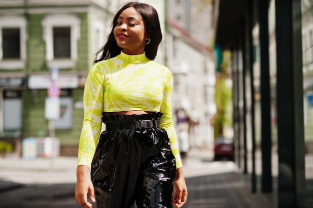 Portrait de jeune belle femme mannequin afro-américaine portant un haut vert et un pantalon noir brillant au look mouillé