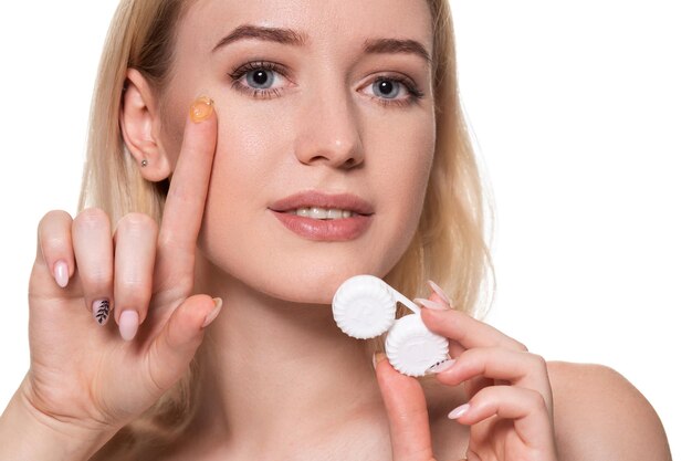 Portrait de jeune belle femme avec maquillage naturel et lentille de contact à la main. Gros plan sur un modèle féminin tenant une boîte à lentilles blanches. Soins oculaires et mode de vie sain. Santé des yeux.