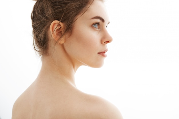 Portrait de jeune belle femme nue tendre avec chignon debout sur fond blanc.