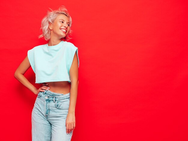 Portrait de jeune belle femme souriante dans des vêtements d'été à la mode Sexy femme insouciante posant près du mur rose en studio Modèle blond positif s'amusant et devenant fou Enthousiaste et heureux