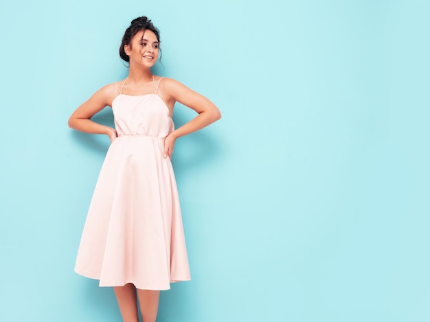 Portrait de jeune belle femme souriante en robe d'été à la mode Sexy femme insouciante posant près du mur bleu en studio Modèle positif s'amusant à l'intérieur Enthousiaste et heureux