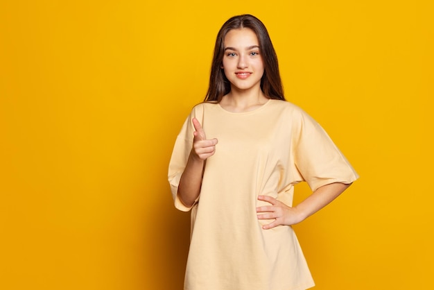 Portrait de jeune belle fille posant isolé sur fond de studio jaune