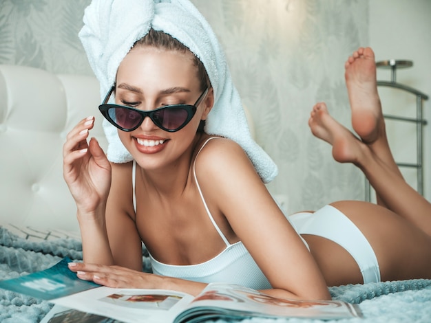 Portrait de jeune belle fille souriante en lingerie blanche et serviette sur la tête