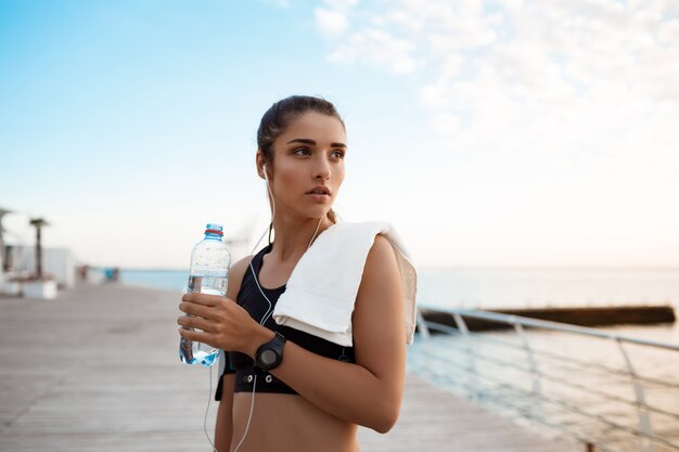 Portrait de jeune belle fille sportive au lever du soleil sur le bord de mer.