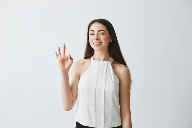 Portrait de jeune belle fille tendre un clin de œil souriant montrant bien.