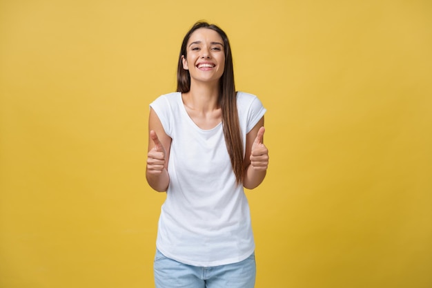 Portrait de jeune belle jolie fille gaie souriante regardant la caméra sur fond jaune Geste du pouce levé