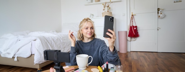 Photo gratuite portrait d'une jeune blogueuse de beauté en train d'enregistrer une vidéo sur une caméra numérique en direct en ligne.