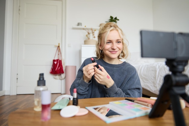 Photo gratuite portrait d'une jeune blogueuse créatrice de contenu enregistrant une vidéo sur une caméra numérique montrant du rouge à lèvres