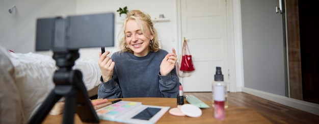 Photo gratuite portrait d'une jeune blogueuse créatrice de contenu enregistrant une vidéo sur une caméra numérique montrant du rouge à lèvres