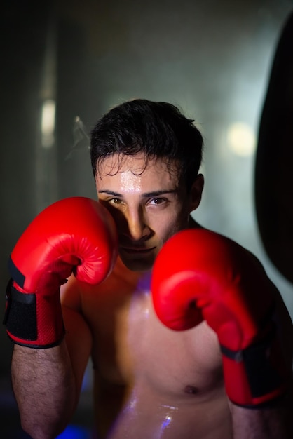 Portrait de jeune boxeur torse nu en gants rouges. Homme multiethnique dédié debout dans la pose de combat. Notion de sportif