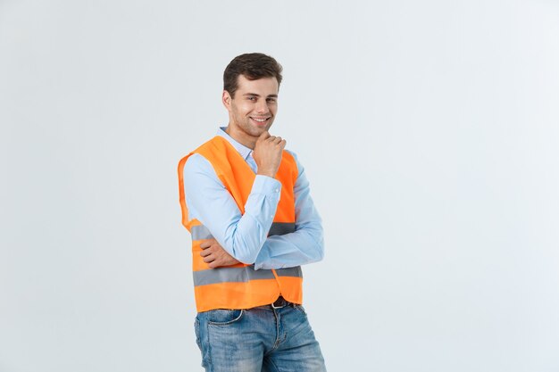 Portrait de jeune contremaître heureux avec gilet orange isolé sur fond blanc.