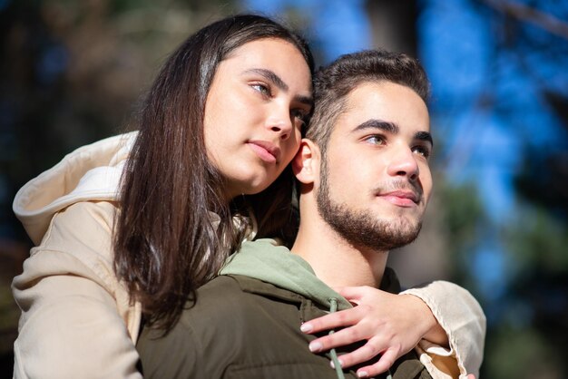 Portrait de jeune couple affectueux étreignant dans la forêt. Femme aux cheveux noirs étreignant un homme barbu sur les épaules. Amour, affection, concept de relation