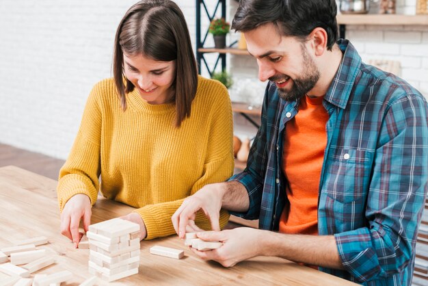 Portrait de jeune couple arrangeant les blocs de bois sur la table