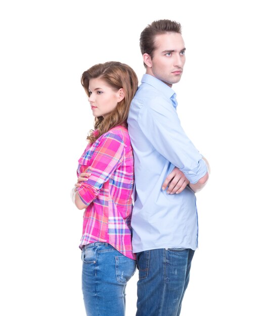 Portrait de jeune couple debout dos à dos et pensant isolé sur un mur blanc.