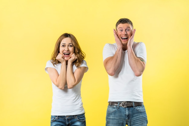 Portrait de jeune couple excité sur fond jaune