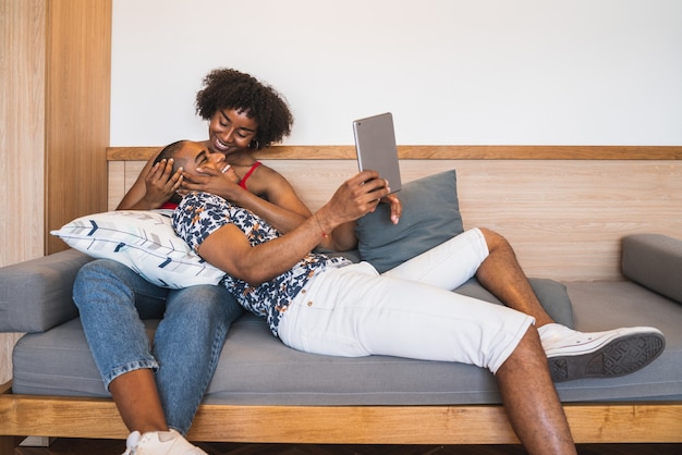 Portrait de jeune couple latin prenant un selfie avec tablette numérique à la maison.