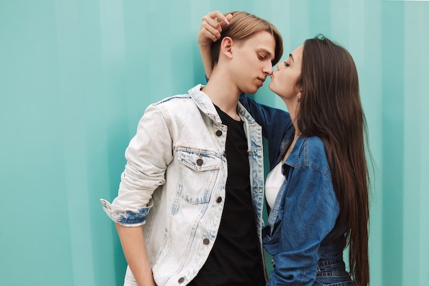 Photo gratuite portrait de jeune couple mignon s'embrassant et s'embrassant en se tenant debout sur fond bleu