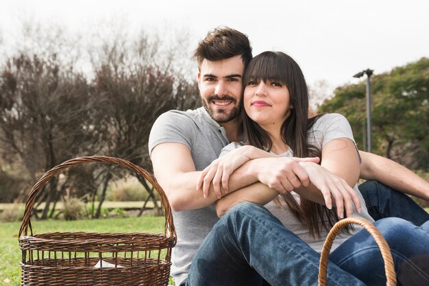 Portrait de jeune couple souriant avec panier de pique-nique dans le parc