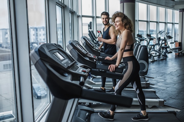 Portrait de jeune couple sportif faisant de l'exercice cardio dans une salle de sport moderne