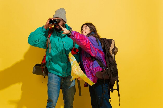 Photo gratuite portrait d'un jeune couple de touristes joyeux isolé sur jaune