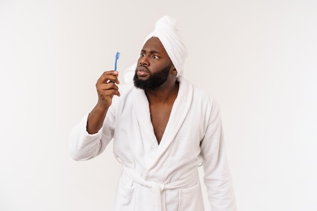 Portrait d'un jeune darkanm heureux se brossant les dents avec du dentifrice noir sur fond blanc