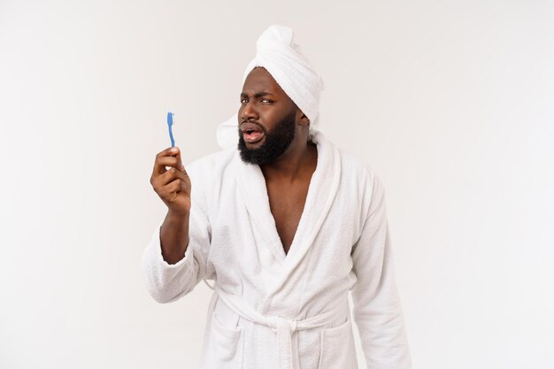 Portrait d'un jeune darkanm heureux se brossant les dents avec du dentifrice noir sur fond blanc