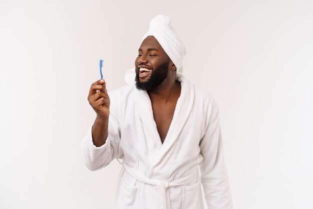 Portrait d'un jeune darkanm heureux se brossant les dents avec du dentifrice noir sur fond blanc