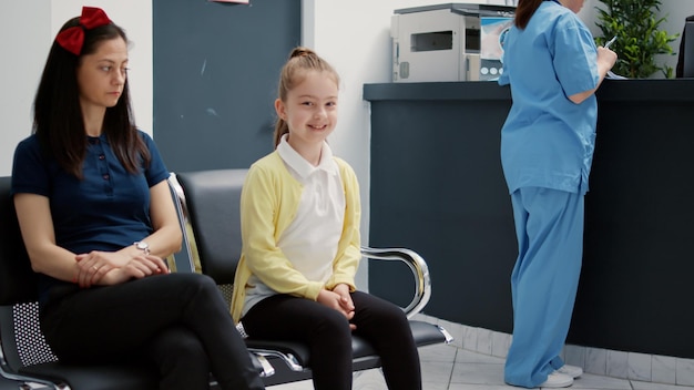 Portrait d'un jeune enfant assis avec sa mère dans le hall de la salle d'attente à la réception de l'hôpital, établissement médical pour faire un examen médical avec un médecin. Salle d'attente pour rendez-vous de visite de contrôle.