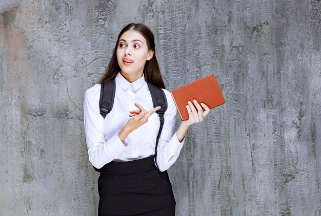 Portrait de jeune étudiant en tenue d'école tenant un livre et posant. Photo de haute qualité