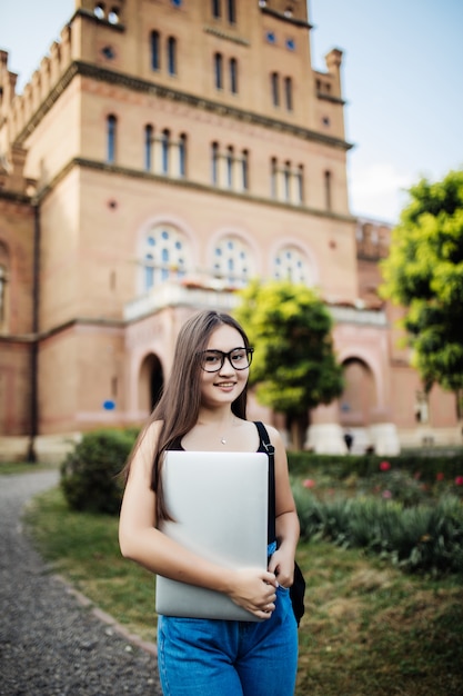 Portrait de jeune étudiante asiatique à l'aide d'un ordinateur portable ou d'une tablette dans une pose intelligente et heureuse à l'université ou au collège