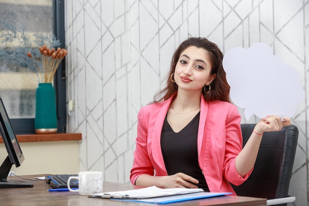 Portrait de jeune femme d'affaires assise derrière le bureau et regardant la caméra