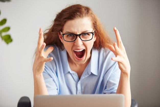 Photo gratuite portrait d'une jeune femme d'affaires attrayante avec un regard frustré travaillant sur ordinateur portable