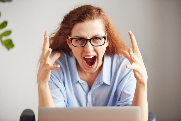 Portrait d'une jeune femme d'affaires attrayante avec un regard frustré travaillant sur ordinateur portable